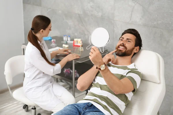 鏡の中の新しい歯科インプラントを屋内で見ている男 — ストック写真