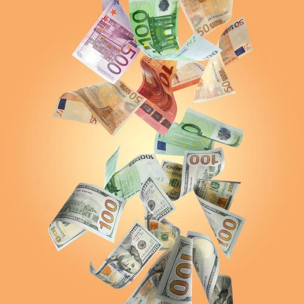 Money exchange. Many dollars and euro banknotes falling on pale orange background