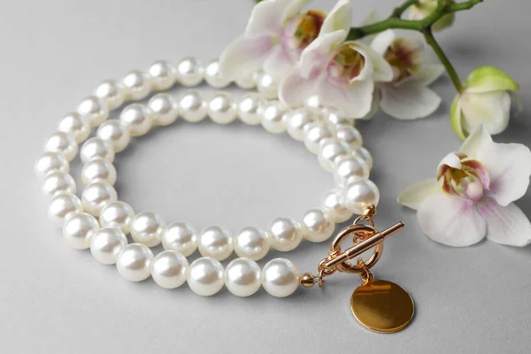 白色背景的精致珍珠项链和兰花 — 图库照片