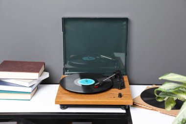 Gri duvarın yanında vinil diski olan şık bir pikap.