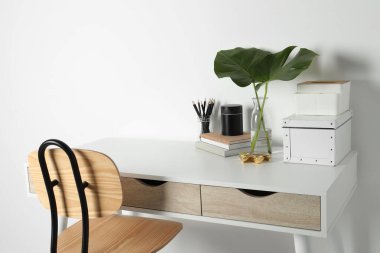 Duvarın yanında beyaz masa olan rahat bir iş yeri.