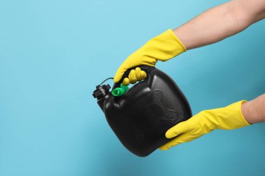 Plastik eldivenli bir adam açık mavi arka planda siyah bir kutu tutuyor, yakın plan. Metin için boşluk
