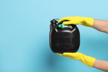 Plastik eldivenli bir adam açık mavi arka planda siyah bir kutu tutuyor, yakın plan. Metin için boşluk