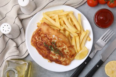 Lezzetli soda, haşlanmış balık, patates cipsi ve limon dilimi açık gri masada servis edilir.