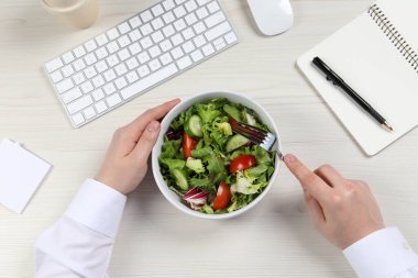 Ofis çalışanı iş yerinde öğle yemeği yiyor.
