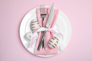 Pembe arka planda boyalı yumurta ve çatal bıçak seti, üst manzara. Paskalya kutlaması
