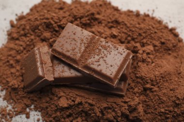 Nefis sütlü çikolata ve kakao tozu ışık masasında, yakın plan.