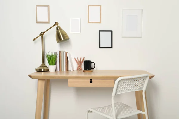 stock image Comfortable workplace with wooden desk near white wall