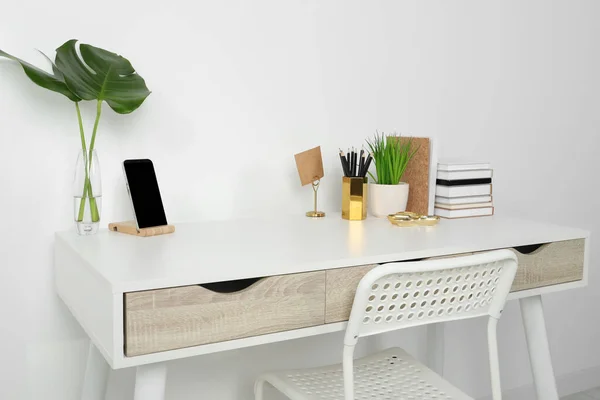 Comfortable workplace with white desk near wall