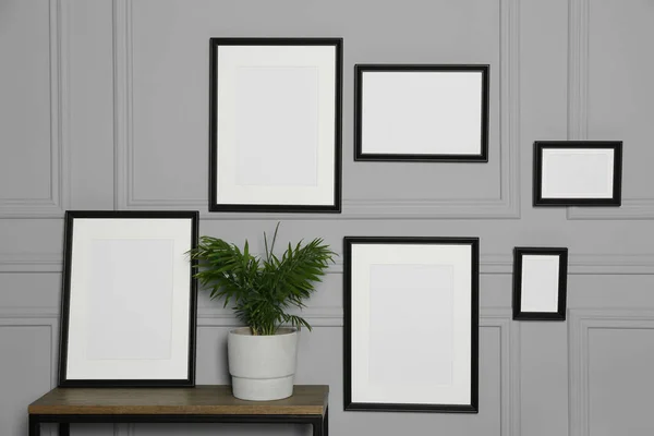 Empty Frames Hanging Grey Wall Wooden Table Indoors — Stock Photo, Image