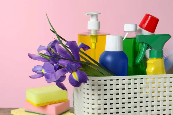 春季清洁 有洗涤剂 鲜花和海绵的篮子 放在桌子上 粉红背景 — 图库照片