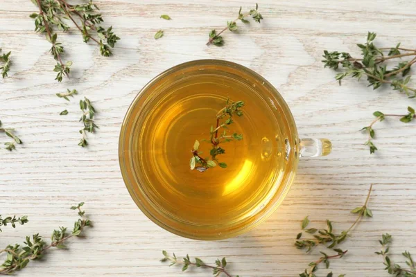 Aromatic herbal tea with thyme on white wooden table, flat lay