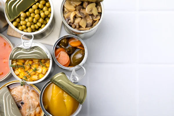 开罐罐 不同的食物放在白色的瓷砖桌上 案文的篇幅 — 图库照片