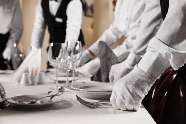 People setting table during professional butler courses in restaurant, closeup