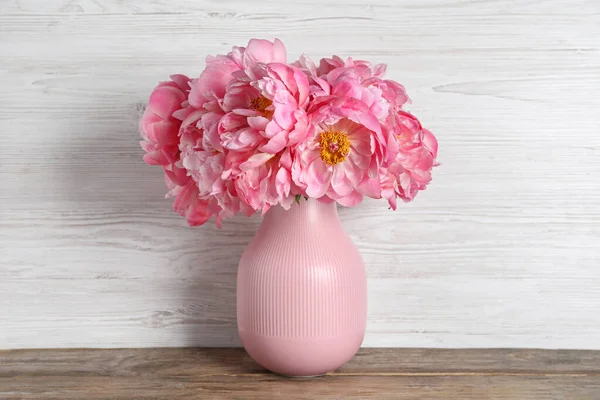 stock image Beautiful bouquet of pink peonies in vase on wooden table