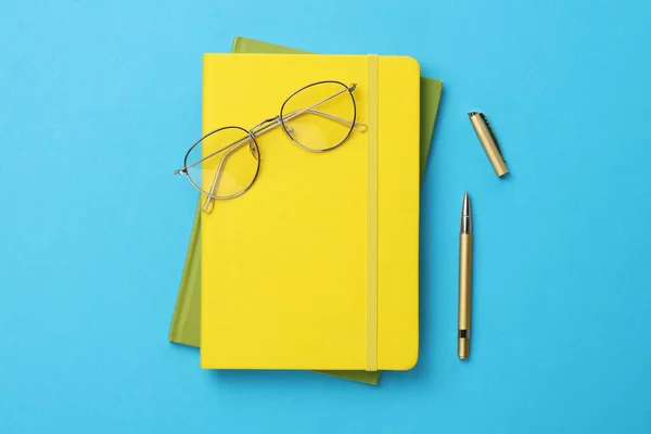 Kugelschreiber Notizbücher Und Brille Auf Hellblauem Hintergrund Flache Lage — Stockfoto