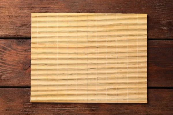 stock image Bamboo mat on wooden table, top view. Space for text