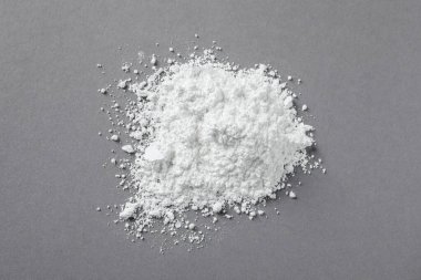 Heap of calcium carbonate powder on grey table, top view