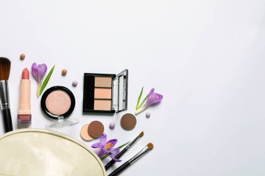 Farklı makyaj ürünleri ve beyaz arkaplanda güzel çiçekler içeren düz kompozisyon, metin için boşluk