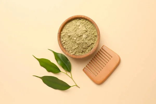 Henna powder, green leaves and comb on beige background, flat lay. Natural hair coloring