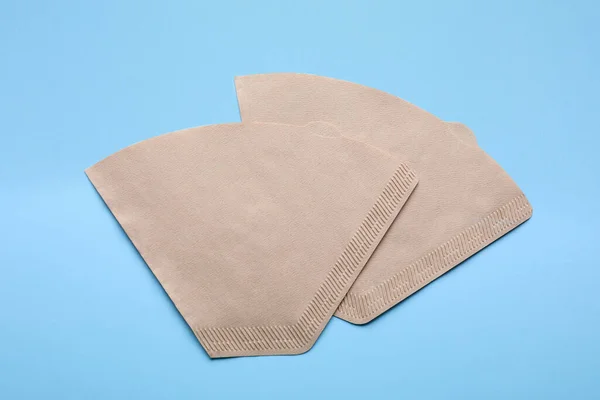 Paper coffee filters on light blue background, flat lay