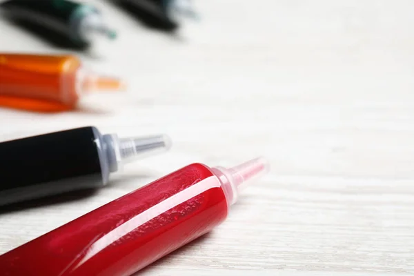 stock image Tubes with different food coloring on white wooden table, closeup. Space for text