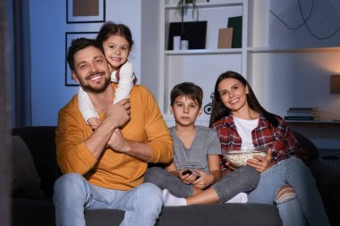 Akşamları evde televizyon izleyen bir aile.