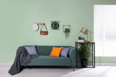 Konsol masasının yanında rahat kanepe, battaniye ve yastıklar bulunan şık bir iç mekan.