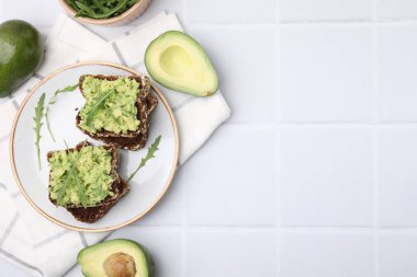 Guacamole, roka ve beyaz fayanslı masada avakado ile nefis sandviçler. Metin için boşluk