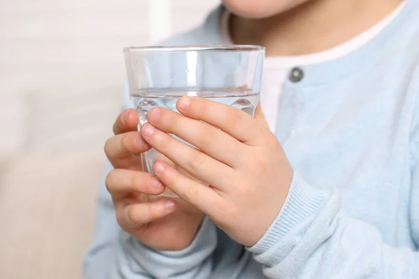 stock image Little girl holding glass of fresh water indoors, closeup