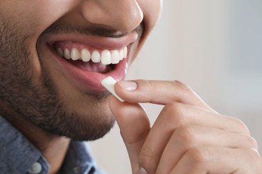 Bulanık arka planda sakızı olan adam, yakın plan.