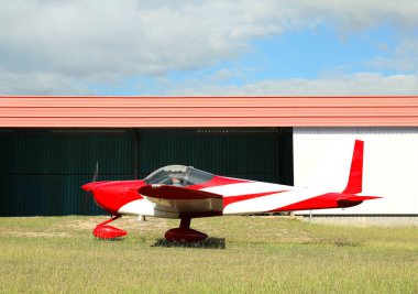 Hangar yakınlarındaki yeşil çimlerde bir uçak.