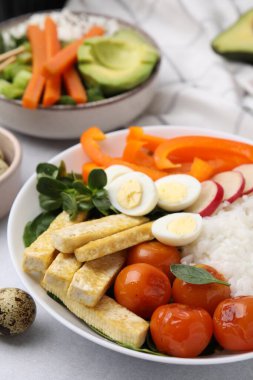 Açık gri masada fesleğen, sebze, yumurta ve tofu ile nefis bir kase.