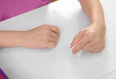 Beyaz masadaki ödevindeki hatayı silen kız.