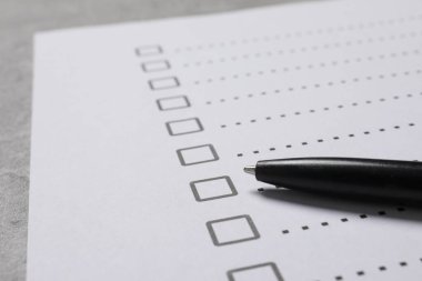 Kağıt kağıtlar, işaretli kutular ve açık gri masa üzerinde kalem, yakın plan. Kontrol Listesi