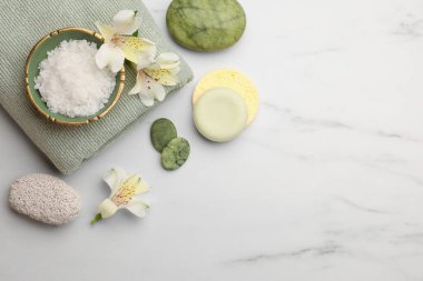 Flat lay composition with spa products and flowers on white marble table. Space for text