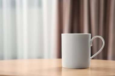 İçerideki ahşap masada beyaz kupa. Tasarım için model