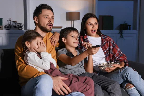 感情的な家族は夜に自宅でテレビを見ている 遠隔操作でチャンネルを変える息子 — ストック写真