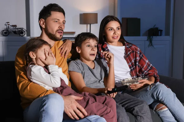 Emotional family watching TV at home in evening