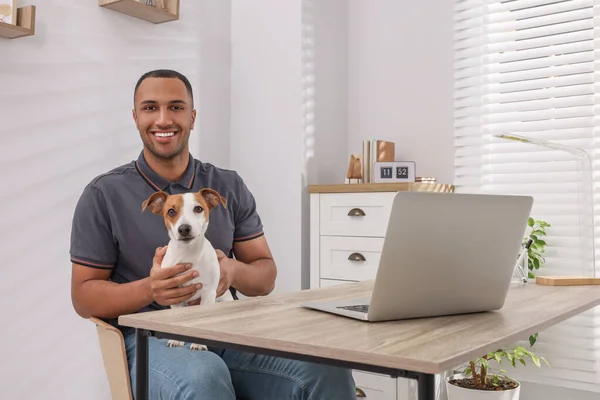 Young man with Jack Russell Terrier at desk in home office