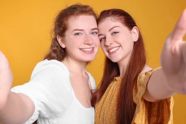 Красивые Молодые Рыжие Сестры Делают Селфи Оранжевом Фоне — стоковое фото