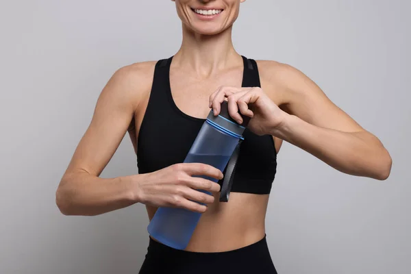 Sportlerin Mit Wasserflasche Auf Hellgrauem Hintergrund Nahaufnahme — Stockfoto
