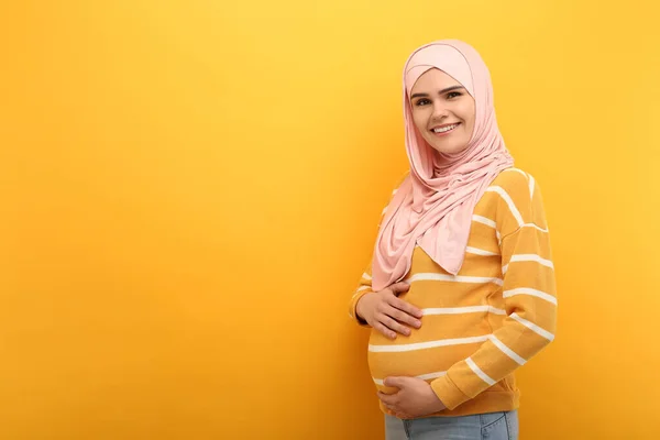 带有橙色背景的头巾的穆斯林孕妇画像 文字空间 — 图库照片