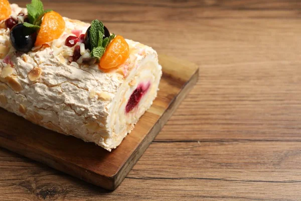 stock image Tasty meringue roll with jam, tangerine slices and mint leaves on wooden table, closeup. Space for text