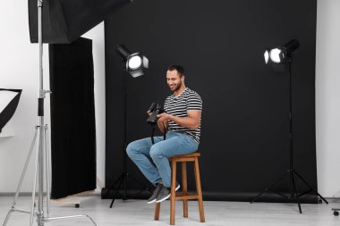 Modern fotoğraf stüdyosunda kamerası olan genç profesyonel fotoğrafçı.