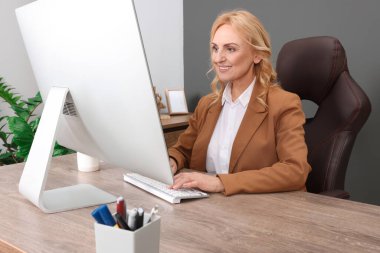 Ofisteki bilgisayarda çalışan bayan patron. Başarılı bir iş kadını.