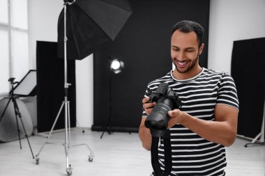 Modern fotoğraf stüdyosunda kamerası olan genç profesyonel fotoğrafçı.
