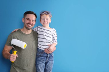 Baba ve oğlu mavi duvarın yanında paten kayıyor, mesaj için yer var. Onarım işi