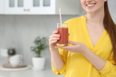 Woman with delicious smoothie in kitchen, closeup. Space for text