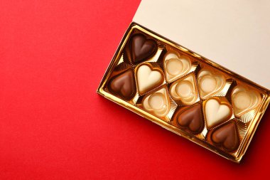 Kırmızı arka planda kısmen boş çikolata kutusu, üst manzara. Metin için boşluk